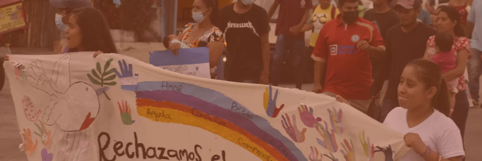 Young people walking with an anti-racism banner depicting a rainbow.