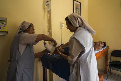 Nun Juana Aguilar, 56, left, and nun Pilar Méndez, 54, right, provide wound care to Guatemalan migrant Miguel Angel López, 17, in migrant shelter Casa del Caminante Jtatic Samuel Ruiz García on Oct. 26, 2018, near Palenque, Chiapas. López lost three toes after slipping off a cargo train on his way to the United States.